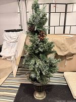 Full view of slim pre-flocked tree with pine cones in urn planter
