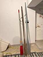 Full view of three oars leaning against wall