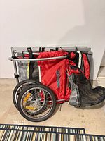 Folded Triumph red/gray trailer with wheels attached to side