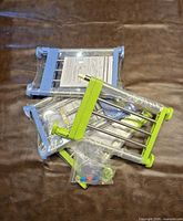 Three packaged adjustable tension shelves showing ABS ends in blue and green with metal tubes and clear spacers