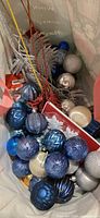 Bag filled with blue, silver, gold ornaments and red packaging visible