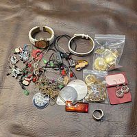 Entire lot spread out showing watch, bracelet, ring, pendants, chains, earrings, bags of findings