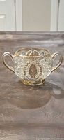 Front view of pressed glass sugar bowl showing double handles and amber tint