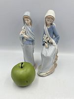 Front view of both Lladro figurines with scale apple
