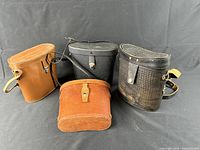 Four closed leather binocular cases: two brown, two black