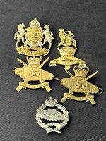 Front view of all five military cap badges on black background