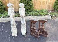 All four salvage pieces: two white newel posts, two dark corbels