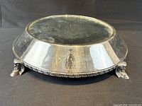 Full view of overturned stand showing mirrored top underside, feet, Greek key rim pattern