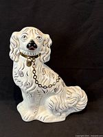 Front view of white porcelain spaniel with gold collar and black swirl decoration