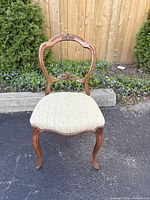 Front view of carved balloon back chair showing upholstery and cabriole legs