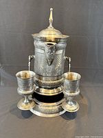 Front view of tilting pitcher on stand with two goblets