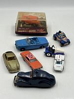 Group shot of all vehicles including boxed AFX slot car and seven loose cars