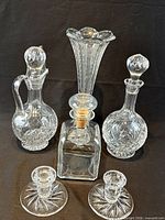 Group shot of all crystal pieces: three decanters, trumpet vase, pair candlesticks