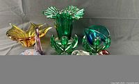Group shot of amber bowl, purple swan, green ruffled vase, teal bowl and one green candle holder