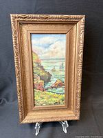 Full view of framed seascape painting on stand