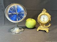 Both alarm clocks beside size-reference apple