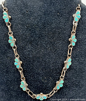 Full view of sterling silver necklace with turquoise floral inlay on display bust