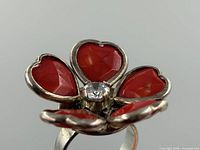 Oblique view showing red enamel petals and central stone