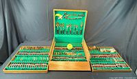 Open wooden case with three sections showing full flatware set and green felt interior