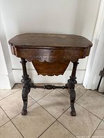 Closed Victorian burr walnut sewing table front view showing inlay, scalloped apron, turned legs, stretcher