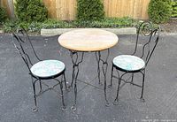 Full view of table and two chairs outdoors on pavement