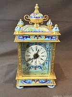 Front view showing cloisonné enamel design, Roman numeral dial and finial
