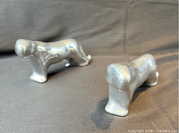 Two polished aluminum panther figurines, front perspective