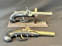 Two pistol lighters on and beside wood stand