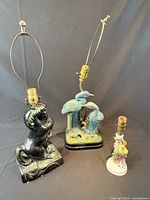 Group shot of three ceramic figural lamps showing overall condition and size relation