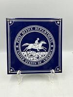 Front view of square enamel sign showing postal rider emblem and mounting holes