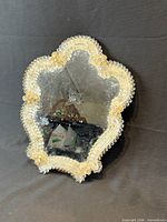 Front view showing scalloped glass frame, gold flecks, mirror surface