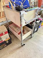 Full view of rolling cart showing chrome frame, two white shelves, casters and handle
