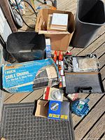 Overall lot showing cable chains box, spark plugs, cardboard box with hardware, distributor cap, mirror, brake parts