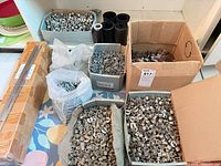 multiple open boxes and bags with assorted cam locks, plastic fittings, and sealed rail bundle