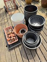 Group of assorted planters, pots, seedling tray, nursery flat and clay blocks on deck