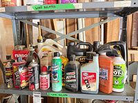 Shelf of mixed motor oils, coolant jugs, ATF, 2-cycle oil and multiple aerosol cans