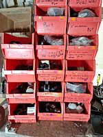 Front view of stacked red/orange bins filled with assorted caster wheels and glides