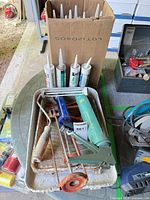 Box of caulking tubes, paint tray, guns, roller