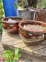 Pair of brown glazed ceramic planters on wooden pallet outdoors