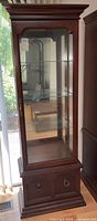 Front view showing glass door, interior shelves, lower cabinet