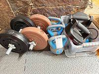 Overall view of dumbbells, plates, kettlebells, push-up handles in storage bin