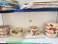 Shelf view of all ceramic pieces: soup bowls, ornamental bowl, creamer on tray, stacked fruit bowls