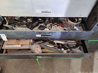 Two open drawers with assorted hand tools, electrical parts and small hardware visible