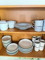 Cabinet view showing entire assortment of cups, mugs, bowls and plates