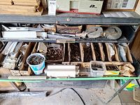 Open metal drawer cabinet showing compartments filled with mixed hardware and casters