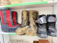 Three pairs of boots on shelf: striped winter boots, faux-fur liners, black Adidas boots
