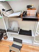 Shelf showing staplers, wood letter tray, file sorter, portfolio, CPU stand