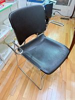 Front angled view of black vinyl chair with chrome sled frame and armrests