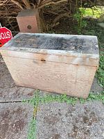 Closed plywood trunk showing weathered exterior and black painted top