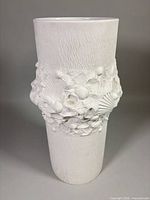 Front view of cylindrical white bisque porcelain vase showing full height and seashell relief band
